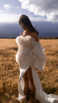 Bride with head bowed in a high-slit gown and petal organza detachable sleeves, cowboy boots, open grassland, My Darling Hurricane Sleeves