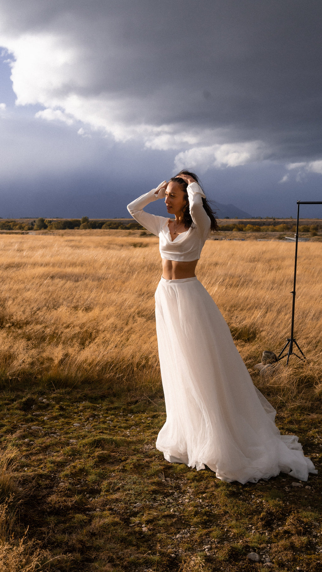 Bride with hands in her hair in a floor-length tulle bridal skirt and cropped top, open tussock field, Olivia Skirt
