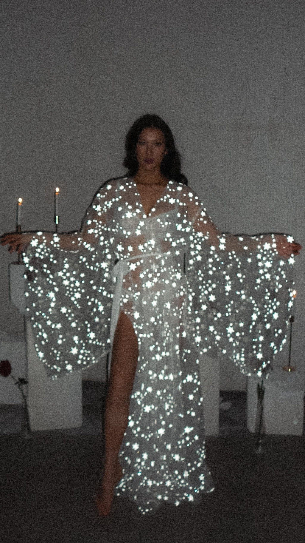 Celestial bridal robe with wide bell sleeves full of stars lit up by the camera flash, candlelit room, Orion Robe by Ephemeris