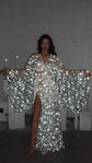 Celestial bridal robe with wide bell sleeves full of stars lit up by the camera flash, candlelit room, Orion Robe by Ephemeris