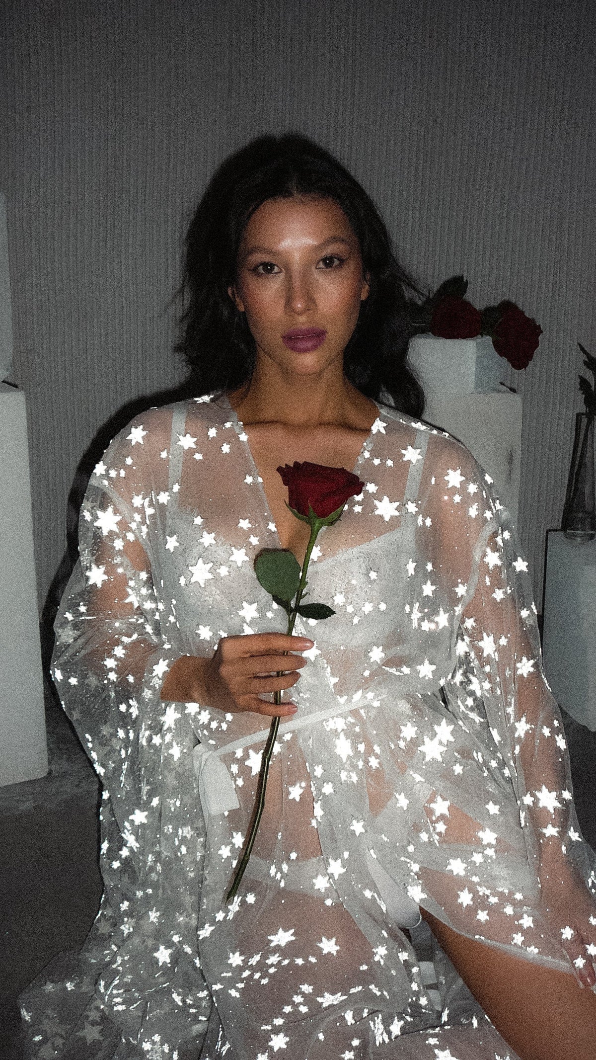 Model kneeling with a single red rose in a belted star bridal robe, sheer tulle over white lingerie, Orion Robe