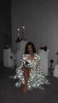 Blurred candlelit shot of a model seated in a sparkling star bridal robe holding a rose, Orion Robe