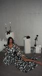 Starry bridal robe flashing bright against a dark floor, model seated with legs stretched out among candles, Orion Robe