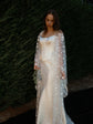 Bride looking down in a long star bridal robe over a satin corset gown, dark hedge behind, evening light, Orion Robe