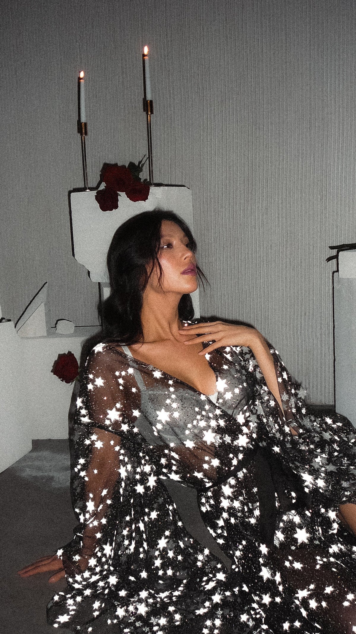 Model seated against a plinth in a black starry bridal robe, hand at her collarbone, candles above, Orion Robe Black