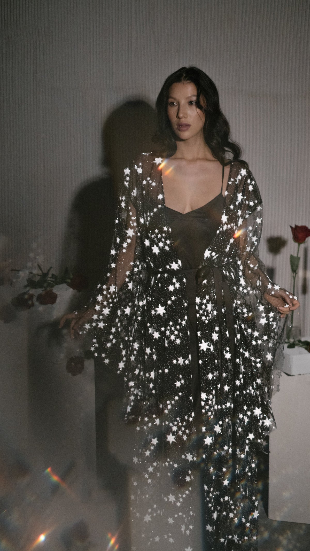 Soft-focus shot of an open black star bridal robe over a black slip, light flare in the foreground, Orion Robe Black