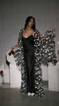 Open black star bridal robe worn over a long black satin slip dress, model holding a rose by white plinths, Orion Robe Black