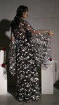 Back view of a black star bridal robe with sweeping bell sleeves, model reaching toward a white plinth, Orion Robe Black