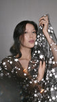 Close portrait with a black star tulle bridal robe sleeve held up beside the face, light flare, Orion Robe Black