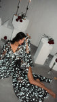 Model sitting on a concrete floor in a black star bridal robe, sleeve held up to frame her face, Orion Robe Black