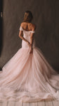 Back view of a blush wedding dress with off-shoulder straps and draped tulle bodice, full train, studio, Peony