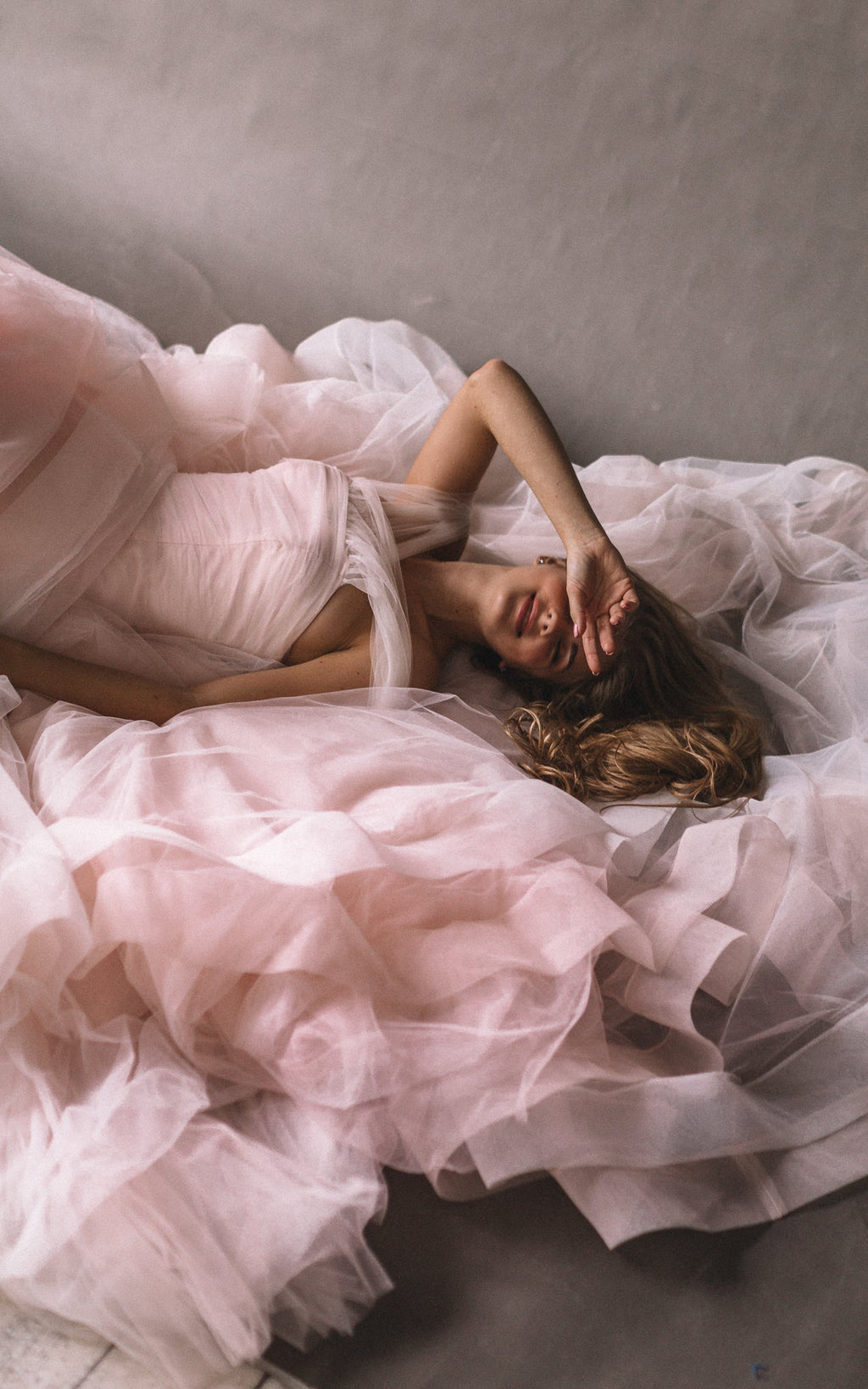 Close-up of a bride lying in layers of blush and ivory tulle, wedding dress skirt in soft folds, Peony
