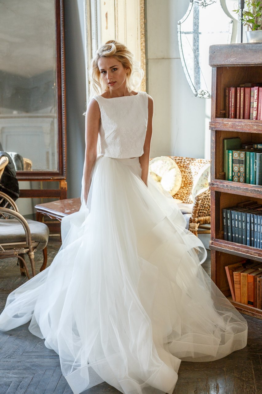 Bride walking in an ivory two-piece wedding dress past bookshelves, layered tulle skirt sweeping the floor, Ready or Not Ivory