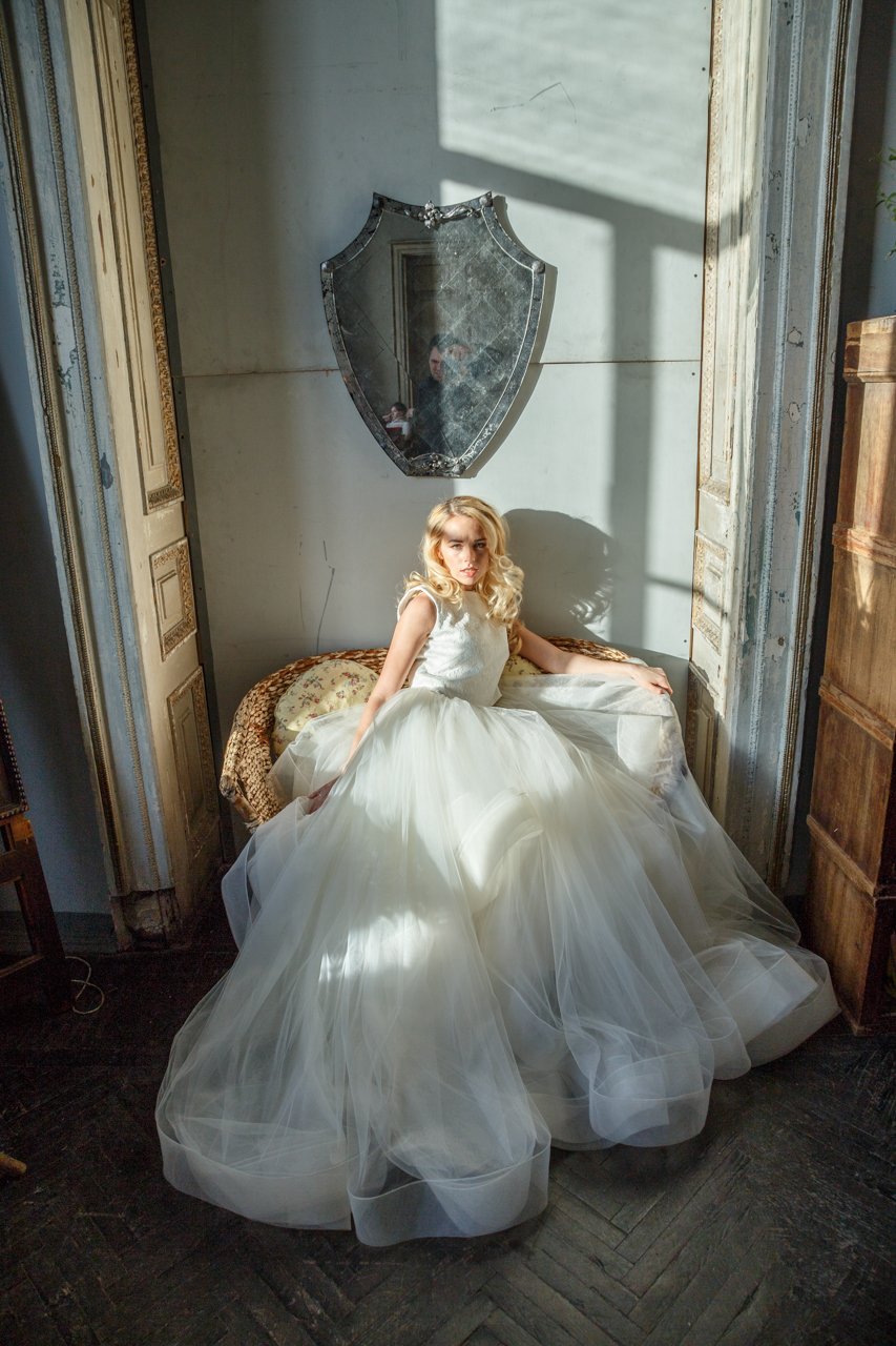 Ivory two-piece wedding dress with a full tulle skirt pooled around a bride seated in a wicker chair, sunlight, Ready or Not Ivory