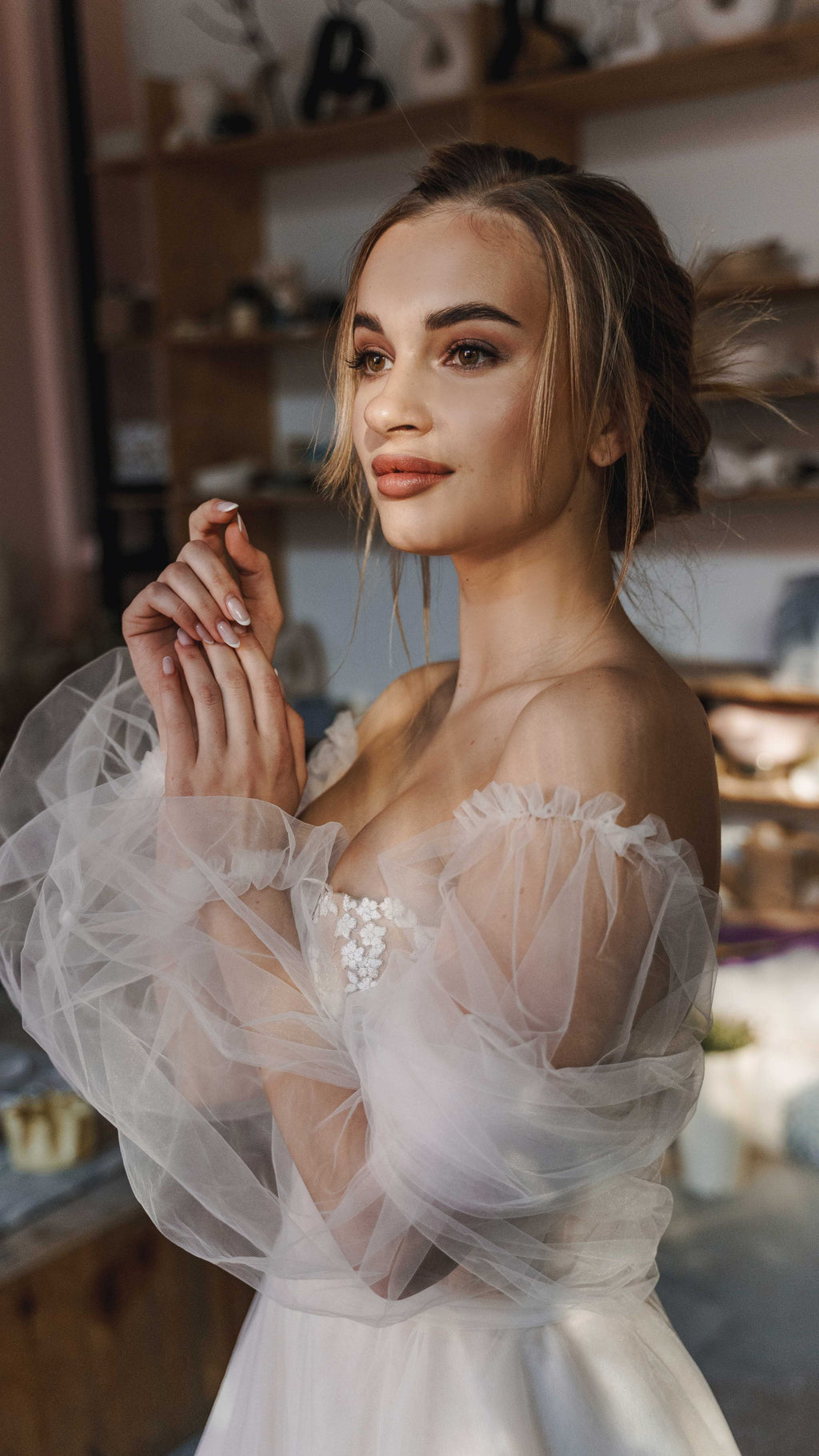 Portrait of a bride with hands together, off-shoulder wedding dress with sheer puff sleeves and flower bodice, Savanna