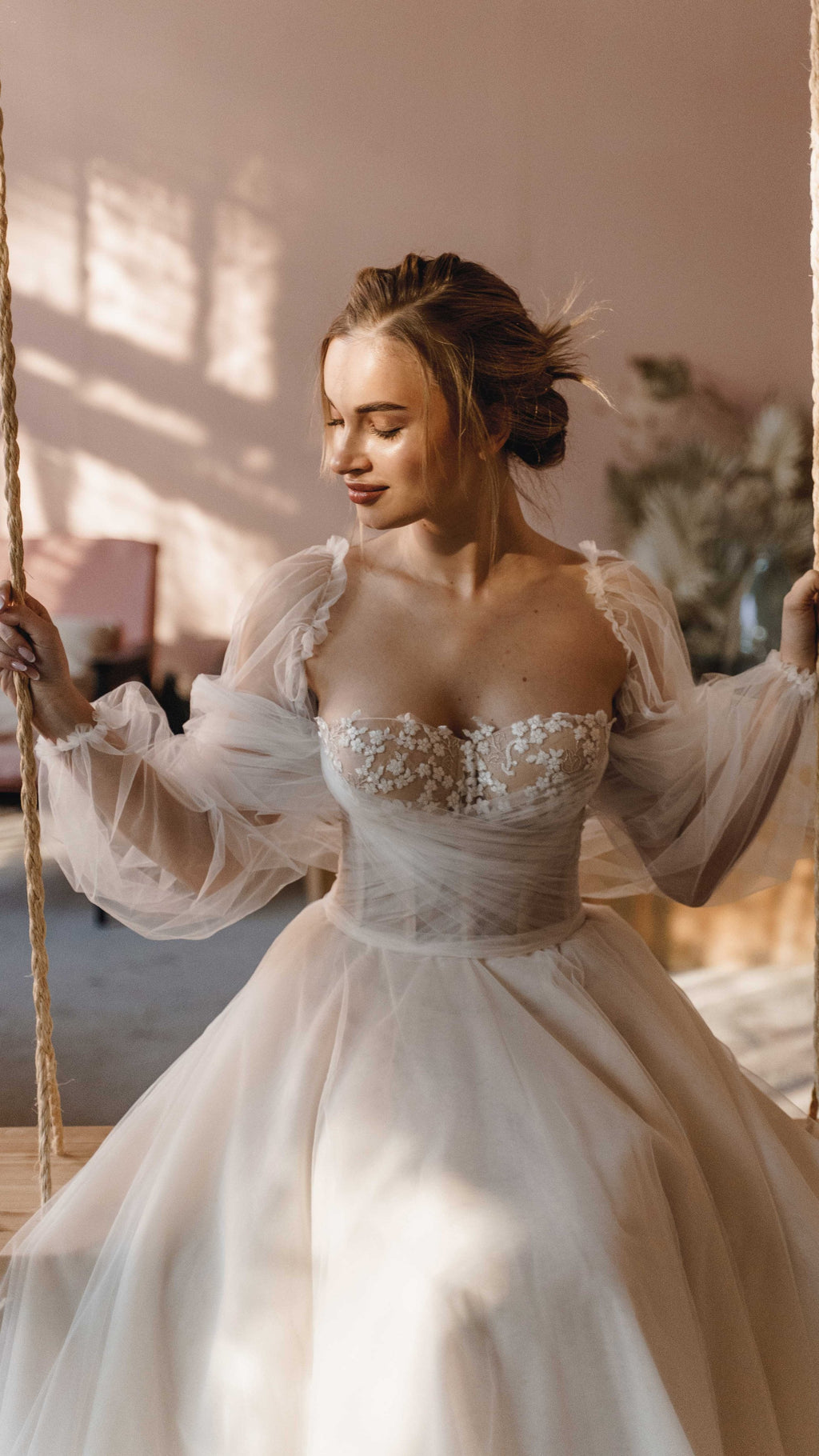 Bride on a rope swing in an off-shoulder tulle wedding dress, cotton flower corset and puff sleeves in sunlight, Savanna