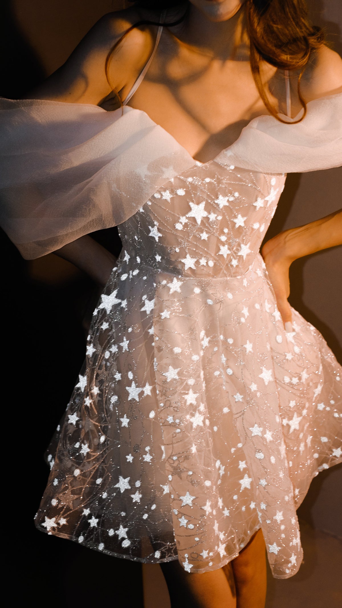 Celestial mini wedding dress in star lace with off-shoulder organza drapes, bodice detail in warm light, Shooting Star by Ephemeris