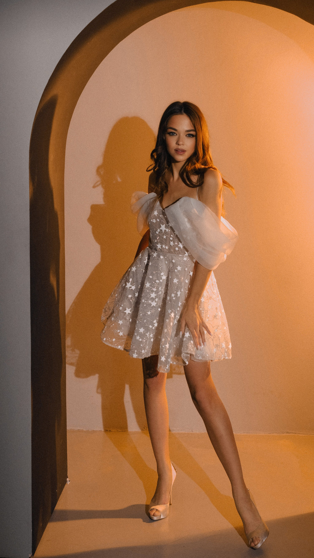 Model in an off-shoulder star mini wedding dress standing in a warm arched alcove, full length, Shooting Star