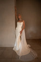 Bride leaning on a wall with one arm raised, satin bridal corset and fitted skirt, chiffon scarf trailing on the tiles, Solana Corset