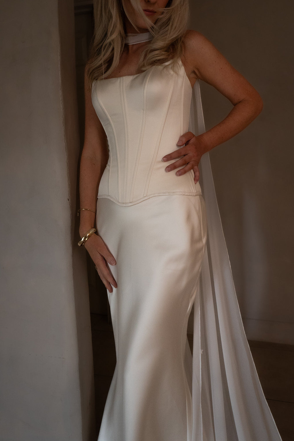 Strapless corset and skirt bridal separates in cream satin, bride with hand on hip and a chiffon scarf at her neck, Solana Ensemble