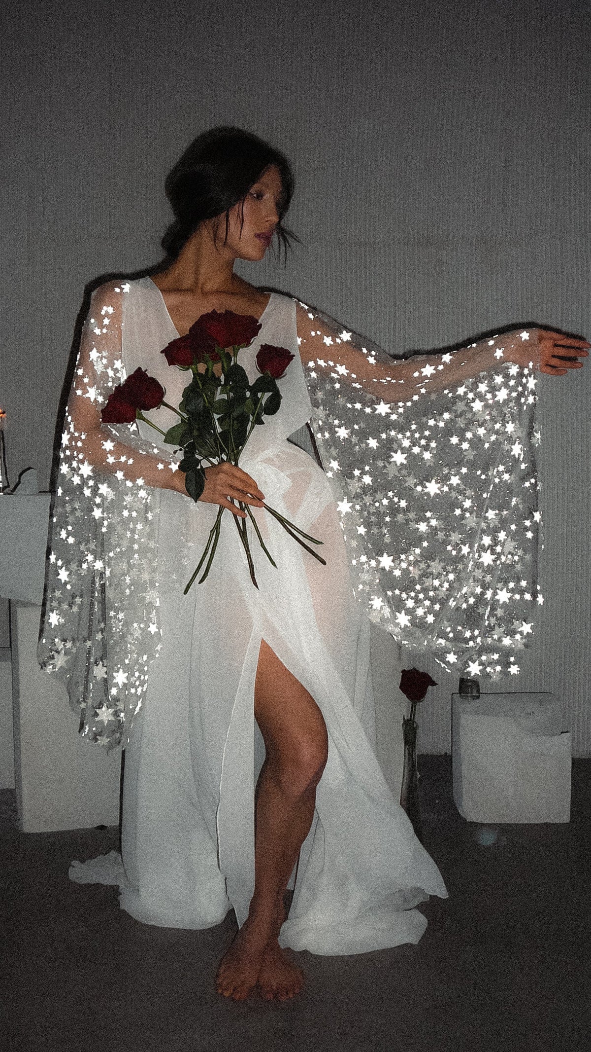 Bride seated with one arm stretched out in a bridal robe, star lace bell sleeve spread wide and a front slit, Stargazer Robe Ivory