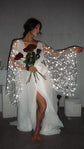 Bride seated with one arm stretched out in a bridal robe, star lace bell sleeve spread wide and a front slit, Stargazer Robe Ivory