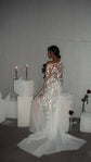 Bride sitting on a white plinth seen from behind, star lace bridal robe with chiffon train fanned on the floor, Stargazer Robe Ivory