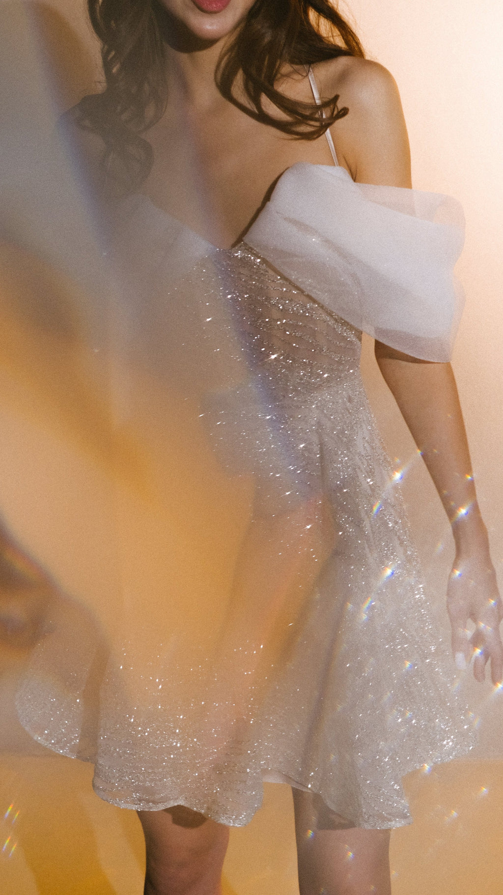 Sparkle lace mini wedding dress with pleated organza off-shoulder drapes, soft-focus prism light over the bodice, Starlight by Ephemeris