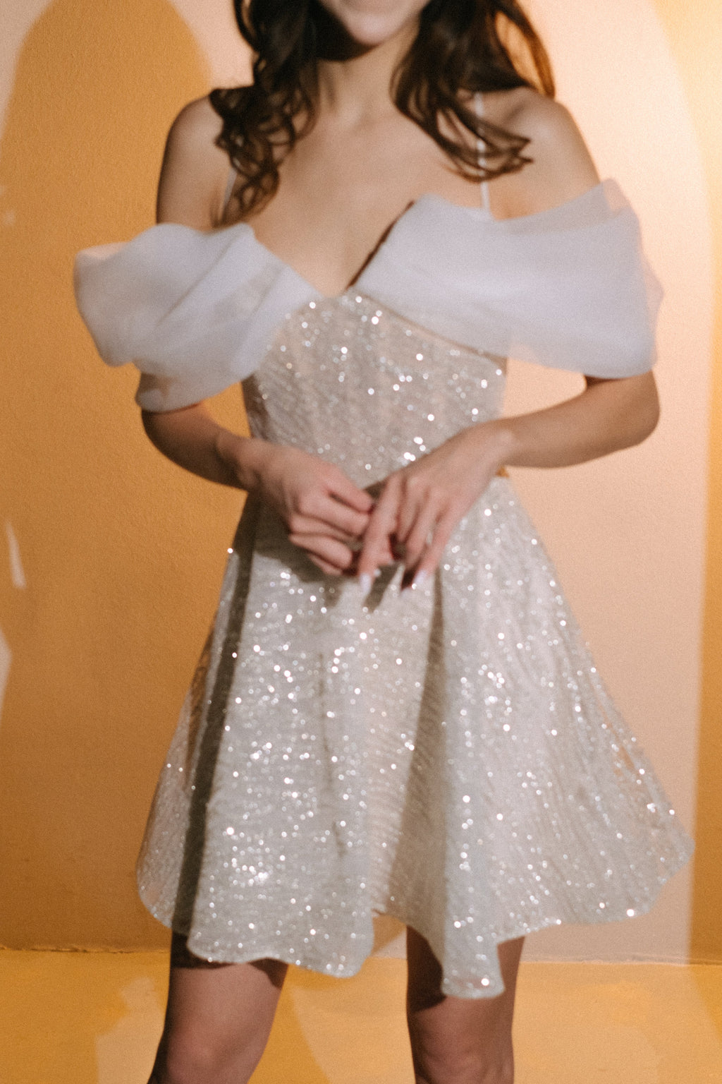 Close crop of a sparkle lace mini wedding dress with a structured bodice and pleated organza off-shoulder drapes, Starlight