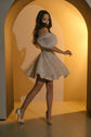 Model twirling in an off-shoulder mini wedding dress, sparkle lace skirt flaring out in a warm arched alcove, Starlight
