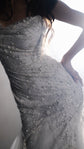 Detail of reflective glass beads and star motifs on the fitted bodice of a wedding dress, hand on hip, Supernova