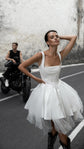 Bride with a hand behind her head in a square-neck corset wedding dress and tulle mini skirt, rider on a motorbike, Swan