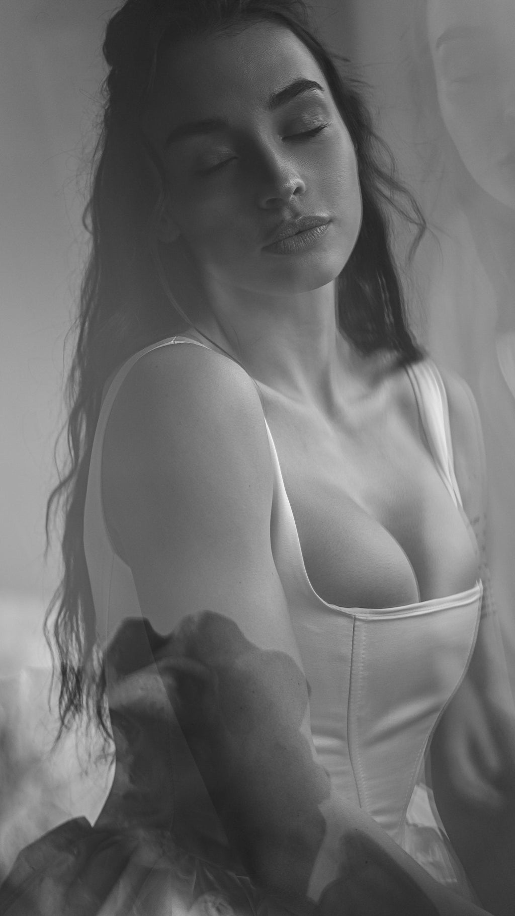 Black and white close crop of a square-neck satin corset wedding dress, model with eyes closed, Swan