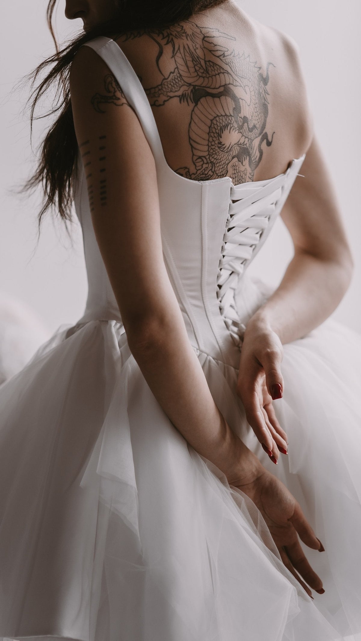 Back view of a satin corset wedding dress with a white lace-up back and wide straps over a tulle skirt, Swan