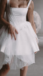 Torso crop of a square-neck satin corset wedding dress with a dropped basque waist and layered tulle skirt, Swan