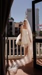 Bride on a sunny balcony in a corset mini wedding dress with a long tulle veil trailing over the tiles, bouquet, Swan