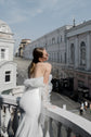 Back view of a crepe sample wedding dress on a city balcony, ruffled tulle at the shoulders and street below, Terra Sample