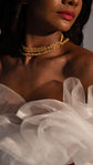 Detail of the ruffled tulle neckline of a sample wedding dress with a gold chain necklace, warm studio light, Terra Sample