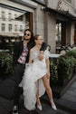 Couple outside a city cafe, bride in an off-shoulder wedding dress with a thigh-high slit and tulle overskirt, Terra