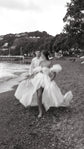 Glossy satin wedding dress with a bandeau bodice and puff sleeves, bride running barefoot on a pebble beach, The Dark Side of The Moon by Ephemeris