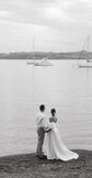 Couple on the shore looking at moored boats, bride in a strapless satin wedding dress with a long train, The Dark Side of The Moon