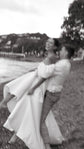 Groom lifting a laughing bride in a satin wedding dress with puff sleeves by the bay, soft motion blur, The Dark Side of The Moon