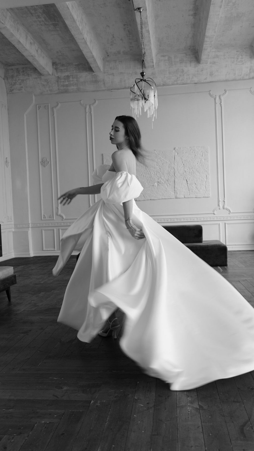 Bride twirling in a satin wedding dress with off-shoulder puff sleeves, full skirt flaring in a panelled room, The Dark Side of The Moon