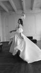 Bride twirling in a satin wedding dress with off-shoulder puff sleeves, full skirt flaring in a panelled room, The Dark Side of The Moon