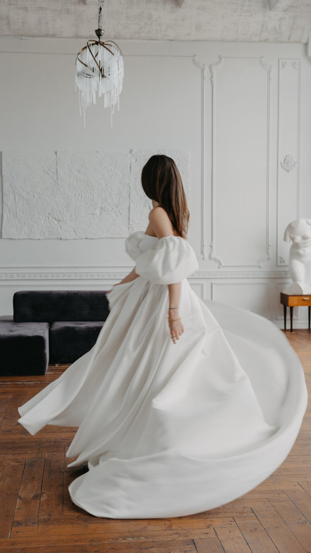 Back view of a bride turning in a satin wedding dress, puff sleeves and the skirt spinning out in a bright salon, The Dark Side of The Moon