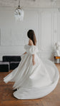 Back view of a bride turning in a satin wedding dress, puff sleeves and the skirt spinning out in a bright salon, The Dark Side of The Moon
