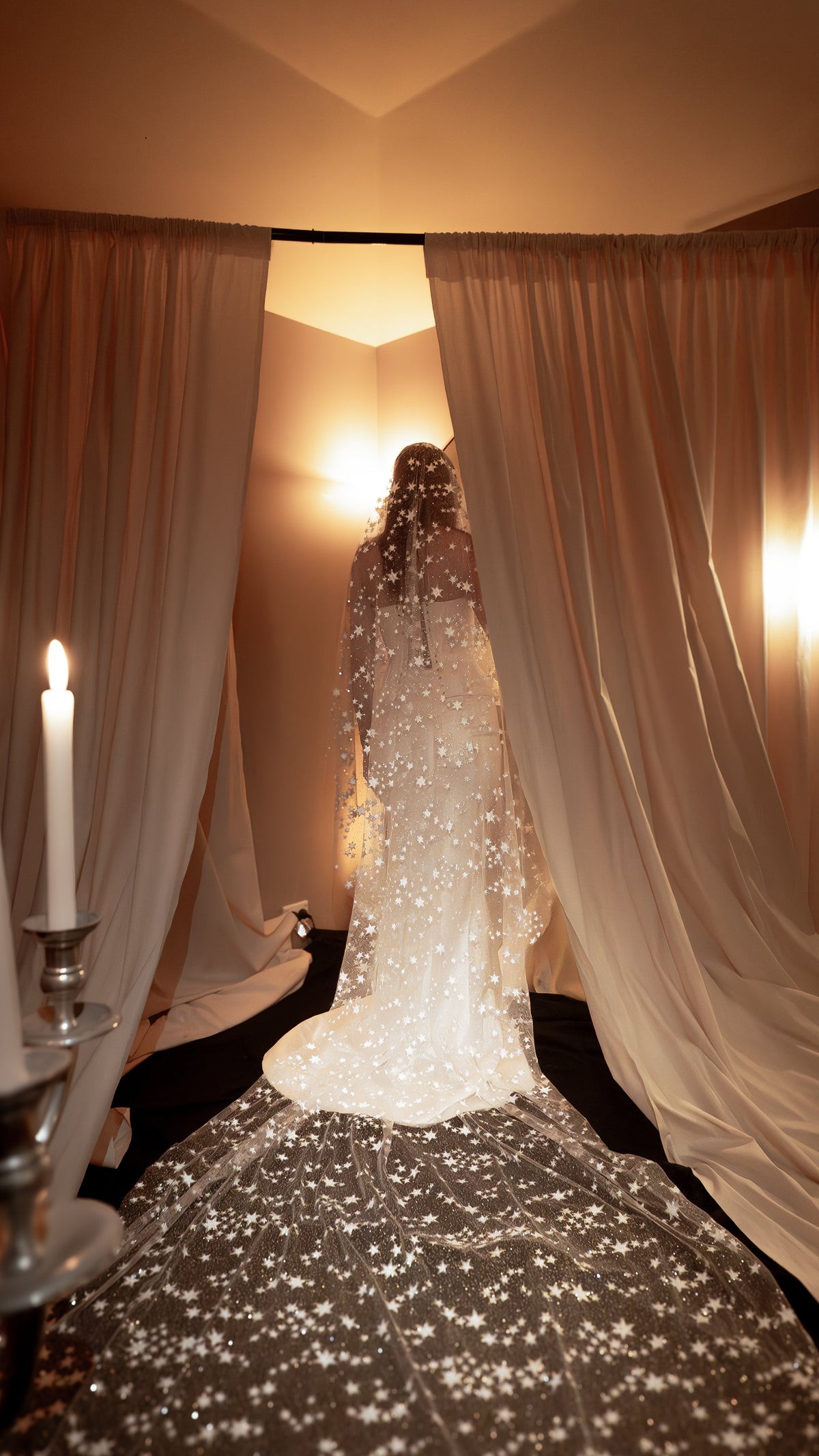 Back view of a bride walking between drapes under a star tulle wedding veil, the cathedral train spread in a wide circle, Velum Veil