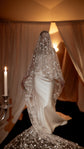 Bride under the blusher of a star-scattered wedding veil, satin gown and long tulle train glowing in candlelight, ethereal, Velum Veil