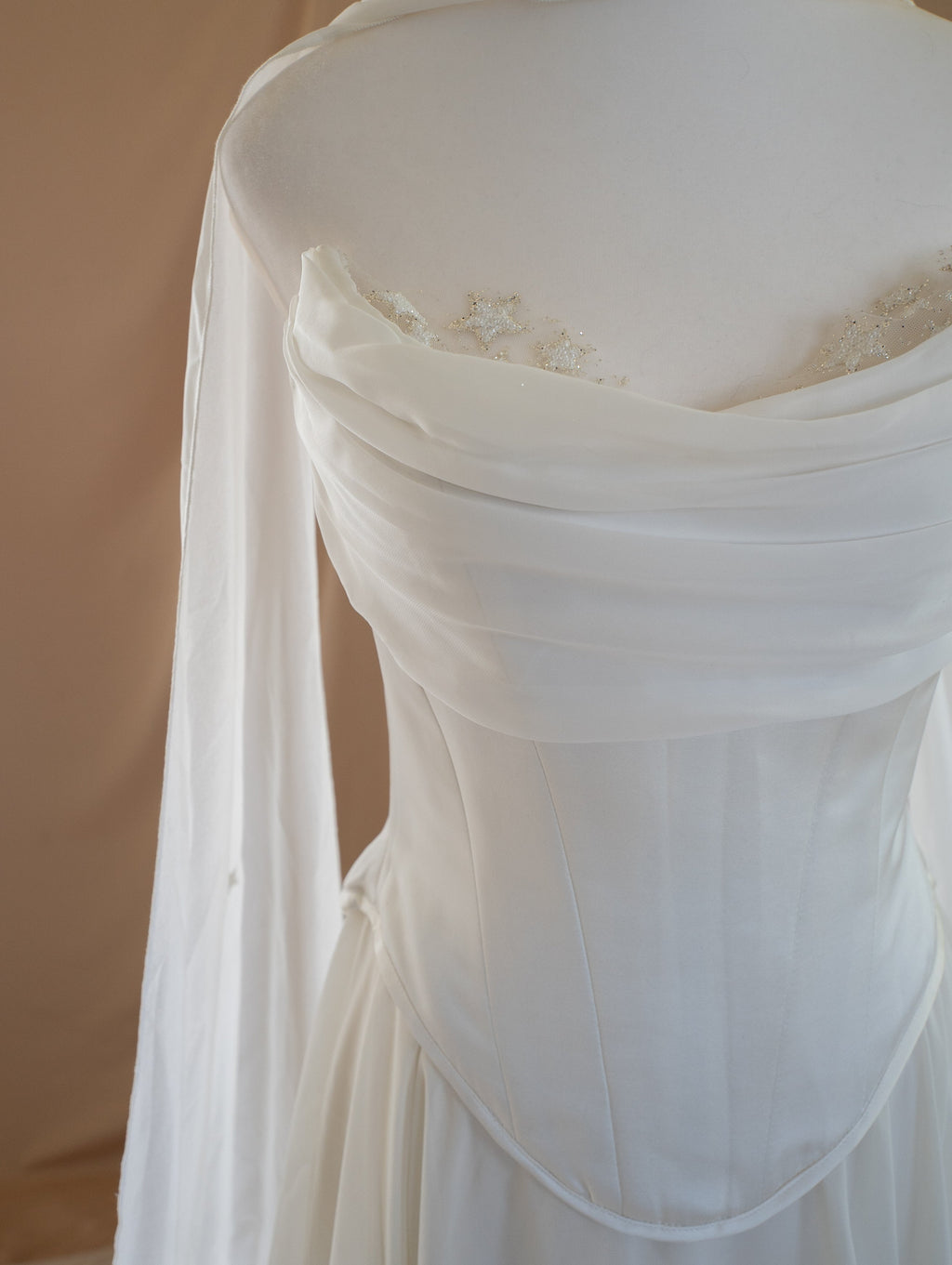 Detail of an ivory bridal corset with a draped chiffon neckline and star lace at the cups, sheer panel behind, Venus Corset