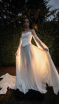 Bride in a corset and skirt lifting the backlit chiffon in a garden at dusk, sleeves trailing, ethereal, Venus Ensemble